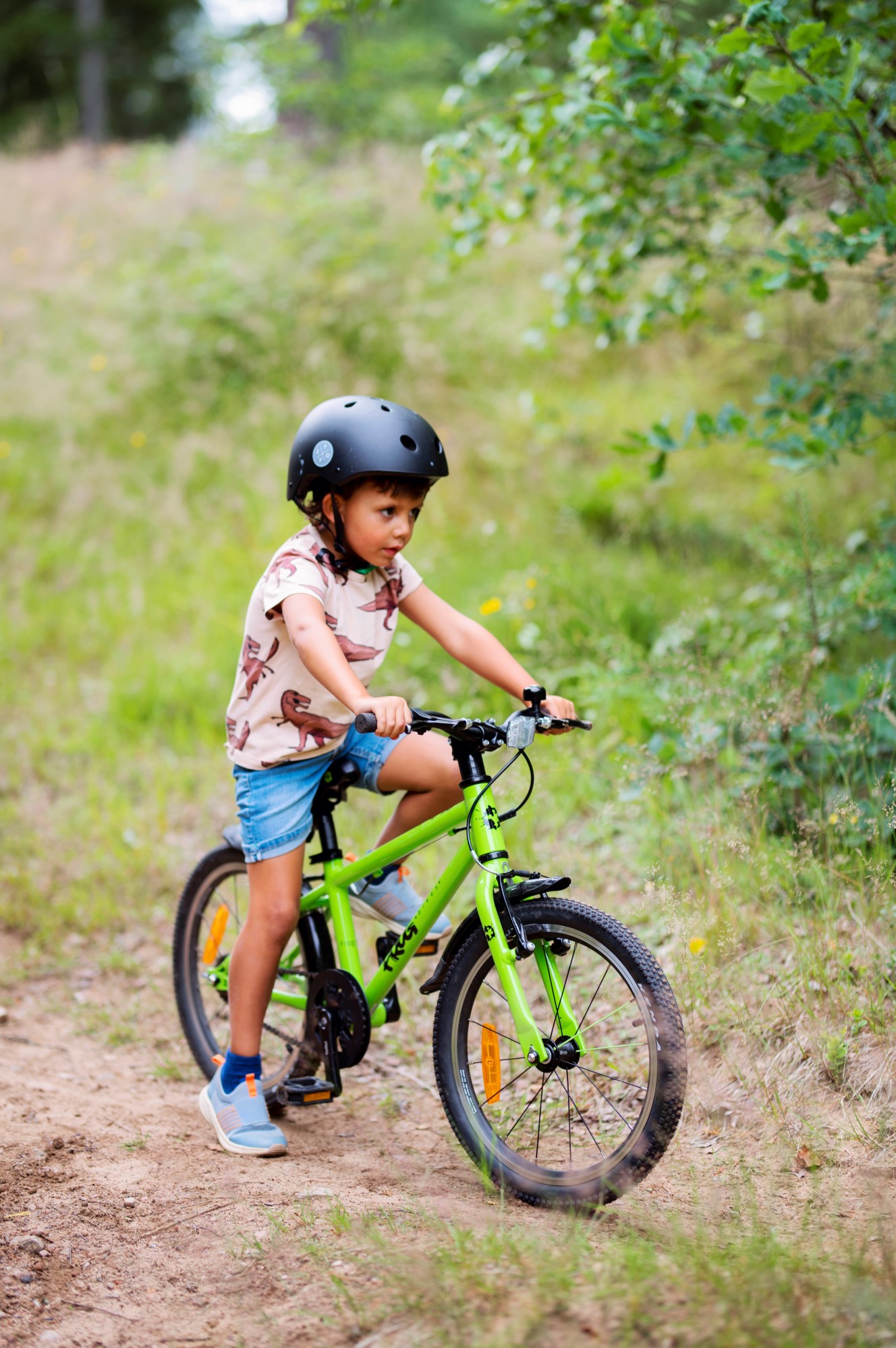 A kid on a green Frog 47 bike in the nature
