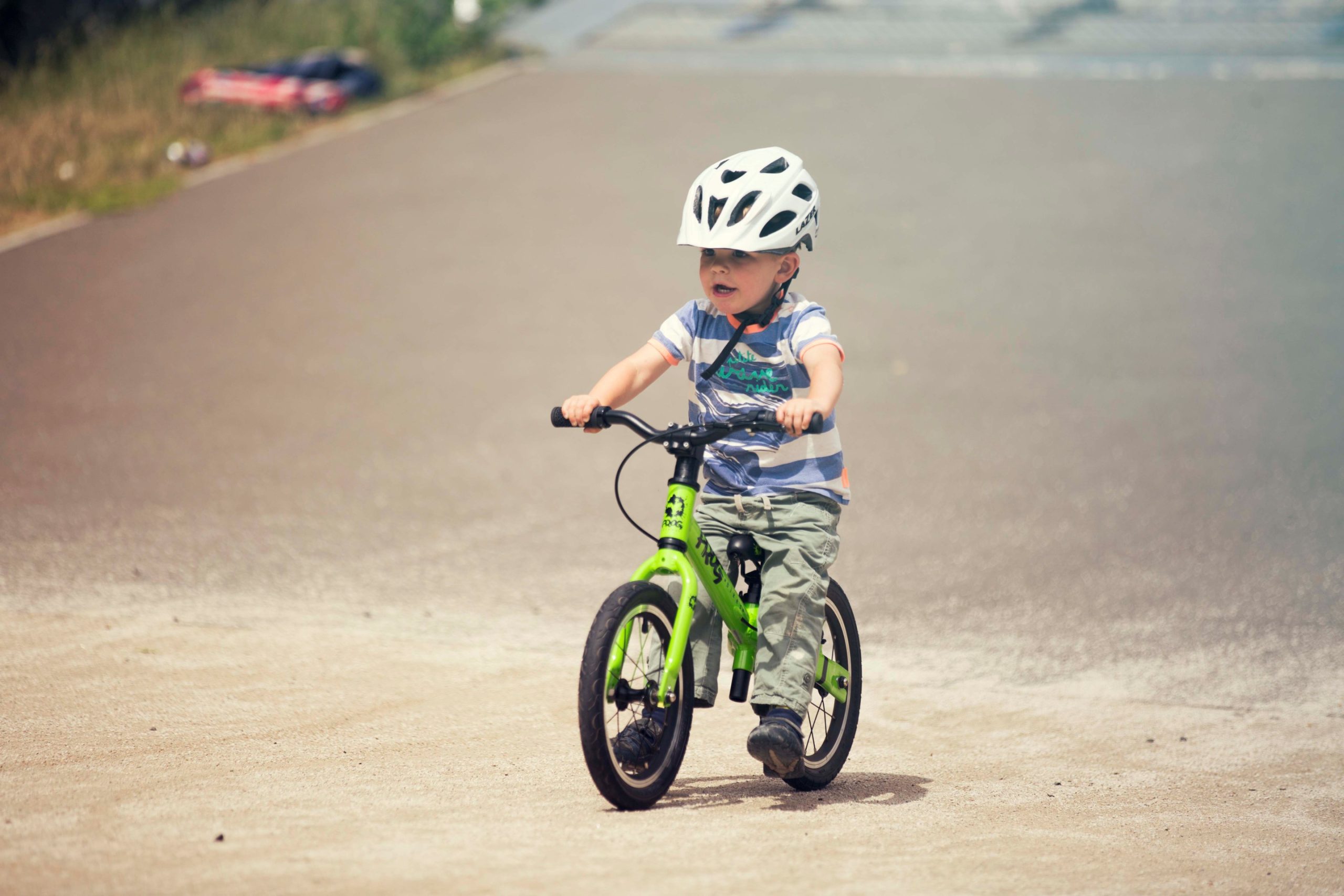 A child riding a green Frog Tadpole Plus bike on a pumptrack