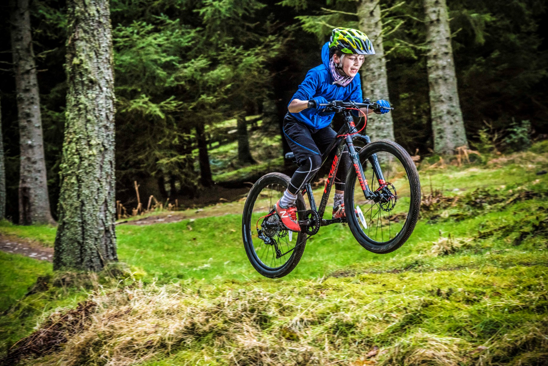 A kid jumping with a Frog Mountain 62 bike